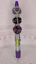 Decorative pen with beads on a clear stand against a white background