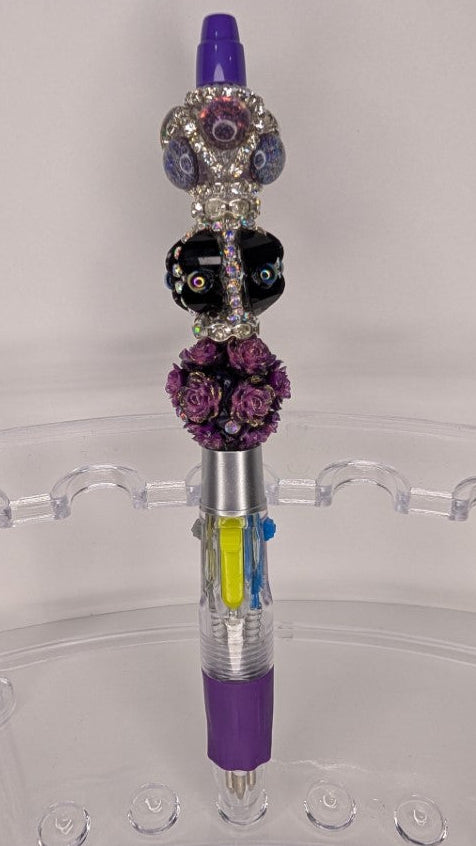 Decorative pen with beads on a clear stand against a white background