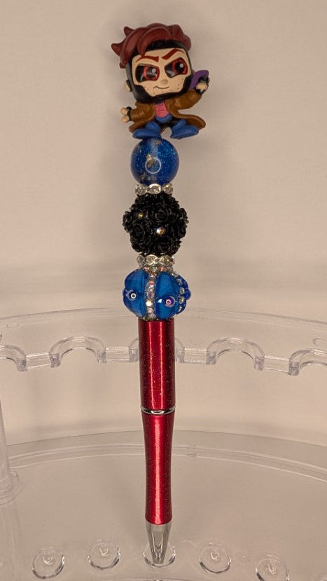 Pen with decorative top featuring a character and colorful beads on a clear stand.