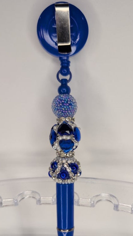 Blue pen with decorative beads on a clear stand against a white background