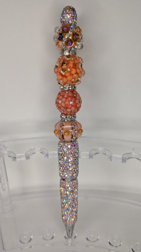 Decorative pen with beads on a clear stand against a white background
