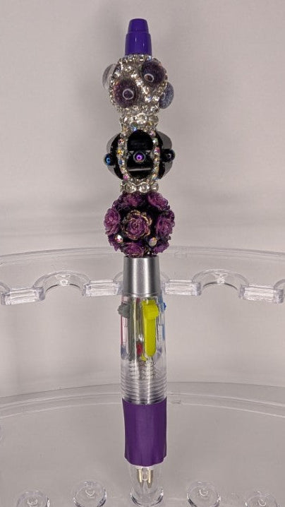 Decorative pen with purple accents on a clear stand against a white background